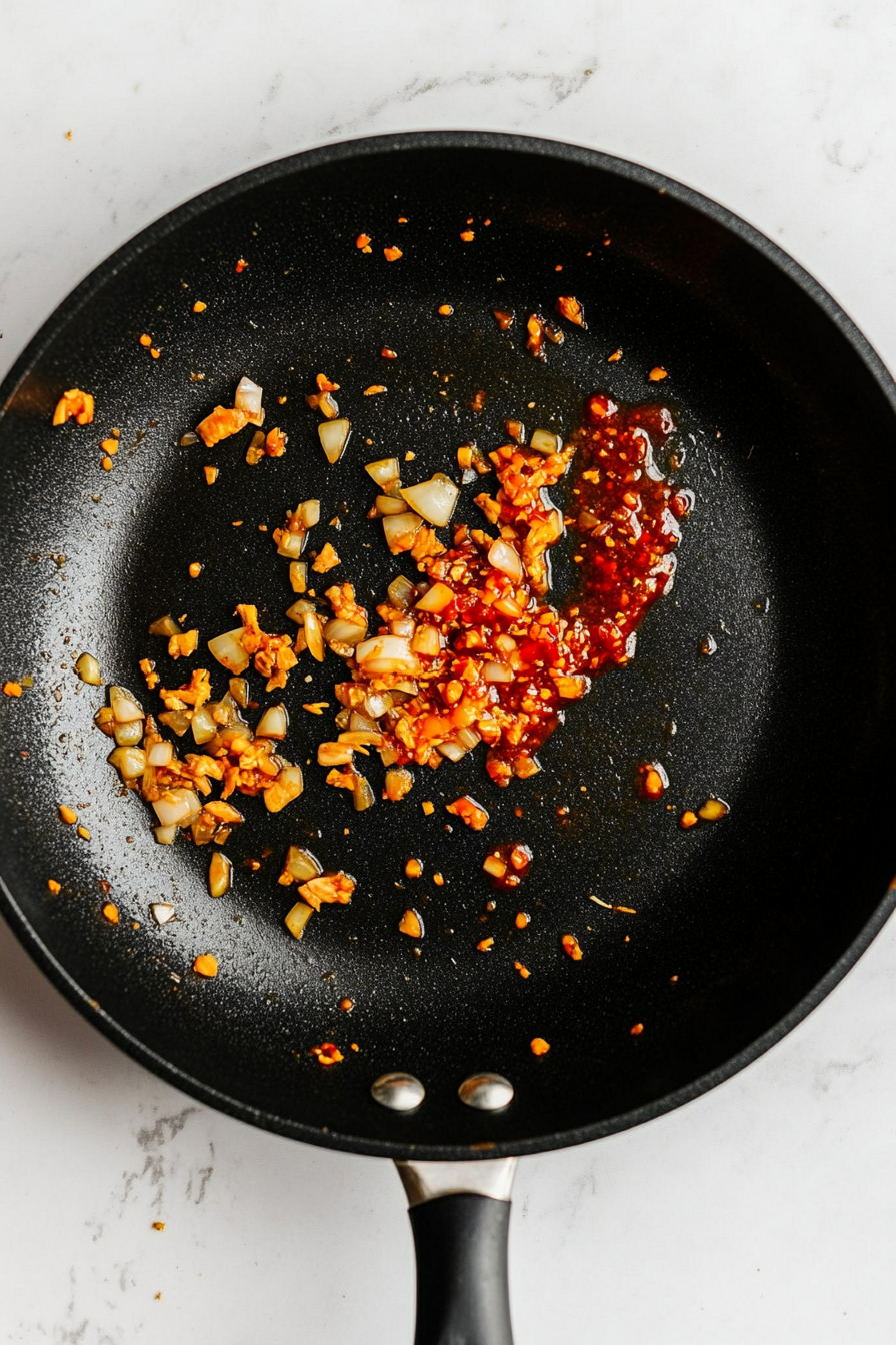 Make the sauce: In the same pan, add garlic, ginger puree, and Sriracha; sauté briefly until fragrant.